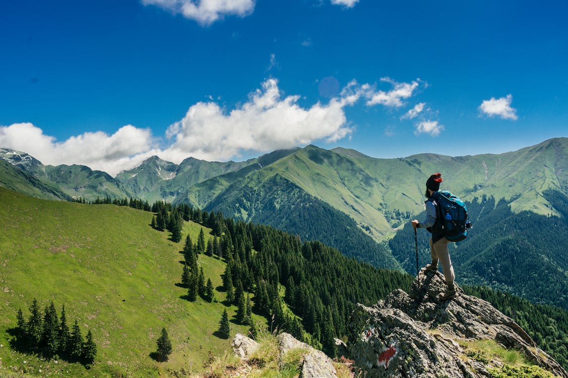 An individual trekking on the picturesque green mountain trails.