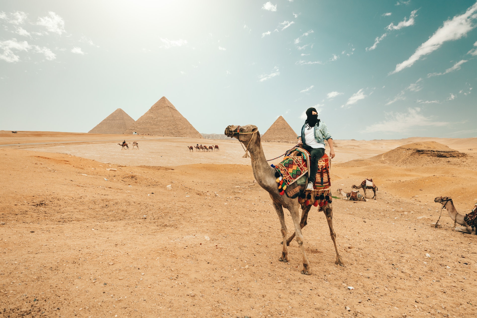 Tourist riding on a camel while exploring egyptian pyramids