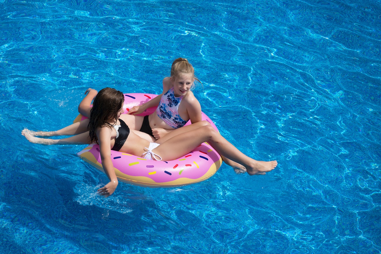 Two girls enjoying on the pink doughnut pool float